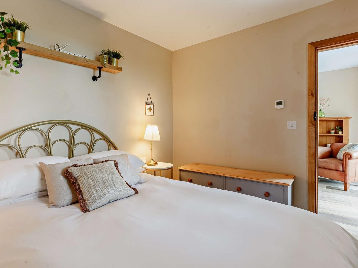 A bedroom with a bed, bedside table, lamp, and a wooden bench.