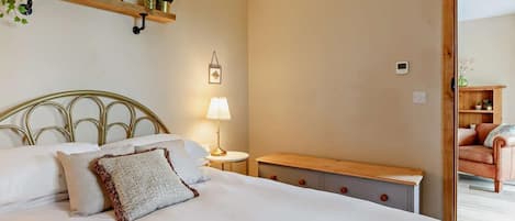 A bedroom with a bed, bedside table, lamp, and a wooden bench.