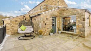 A stone building with a hanging chair, potted plants, and a clear sky. - 5 Bed in Lancaster (oc-90546) (Bentham)