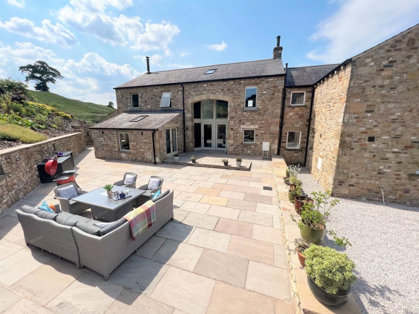 A stone house with a patio area featuring outdoor furniture and potted plants.