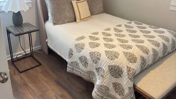 Een slaapkamer met een bed, nachtkastje, plafondventilator en wanddecoratie.