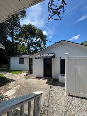 A residential building with a covered porch, a gated entrance, and a small front yard.