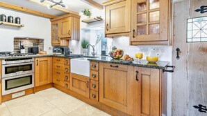 Eine Küche mit Holzausstattung, einem Herd, einem Backofen und einer Spüle.