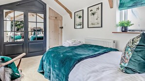 Ein Schlafzimmer mit einem Bett, einer Glastür, einem Heizkörper und gerahmten Bildern an der Wand.