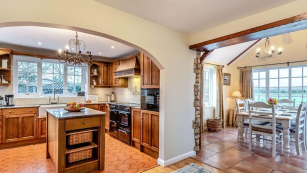 A spacious kitchen with wooden cabinets, a central island, and a dining area with a table and chairs. - 3 Bed in Lincoln (oc-90396) (Washingborough)