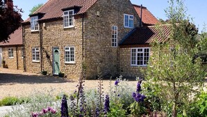 A stone house with a tiled roof, a green door, and a gravel driveway. - 3 Bed in Lincoln (oc-90396) (Washingborough)