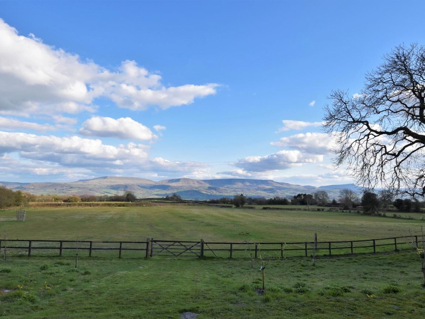 Ländliche Landschaft mit Zaun, offenen Feldern und fernen Hügeln.