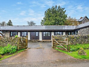 A stone building with a wooden door and windows, surrounded by greenery and a stone wall. - 2 Bed in Dulverton (oc-90558) (Dulverton)