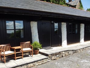 A building with a stone foundation, wooden benches, and a potted plant. - 2 Bed in Dulverton (oc-90558) (Dulverton)