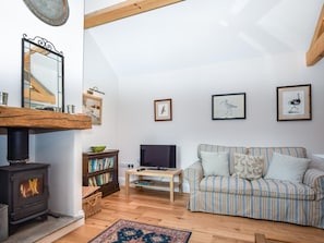 Ein gemütliches Wohnzimmer mit Kamin, einer gestreiften Couch, einem Fernseher und gerahmten Kunstwerken an der Wand.