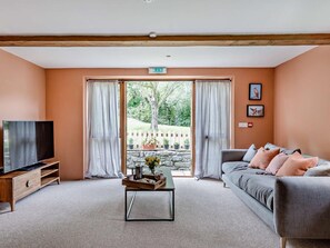 Ein Wohnzimmer mit Fernseher, Sofa und Couchtisch mit Tablett.
