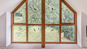 Ein Zimmer mit einem großen, achteckigen Fenster mit Blick auf einen Garten und Bäume.