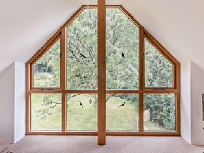 Ein Zimmer mit einem großen, achteckigen Fenster mit Blick auf einen Garten und Bäume.
