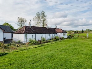 A white house with a brown roof, surrounded by a green lawn and trees. - 2 Bed in Bonnybridge (oc-90602) (Bonnybridge)