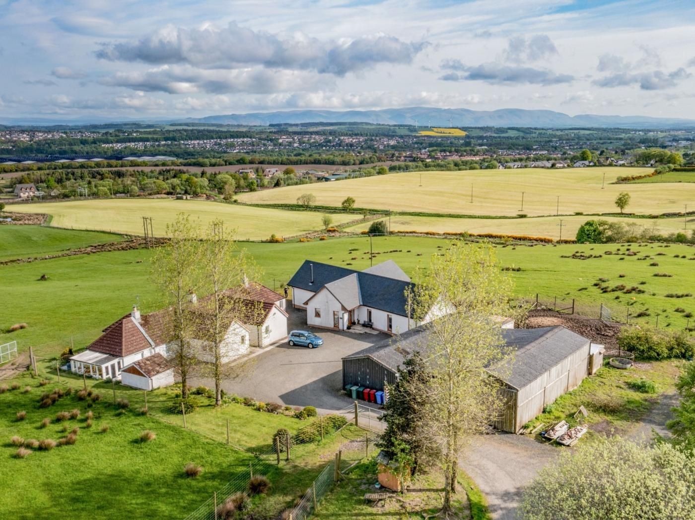 A rural property with a large barn, a farmhouse, and open fields.