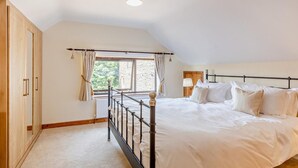 Une chambre à coucher avec un lit, une fenêtre avec des rideaux, un radiateur et une armoire en bois.