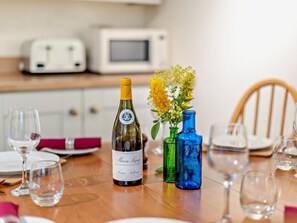 A dining table with a bottle of wine, two vases with flowers, and empty wine glasses. - 2 Bed in Kidderminster (oc-90642) (Stottesdon)