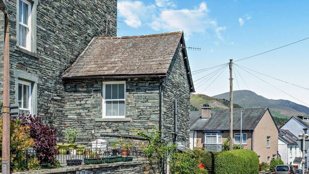A stone building with a pitched roof, a window, and a street sign indicating 'Corn Street.' - 1 Bed in Keswick (oc-90646) (Keswick)