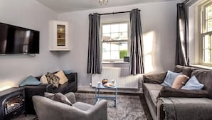 A living room with a fireplace, two sofas, a television, and a radiator. - 1 Bed in Keswick (oc-90646) (Keswick)