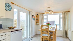 Eine Küche mit Esstisch, Stühlen, einer Uhr und einem Fenster mit Vorhängen.