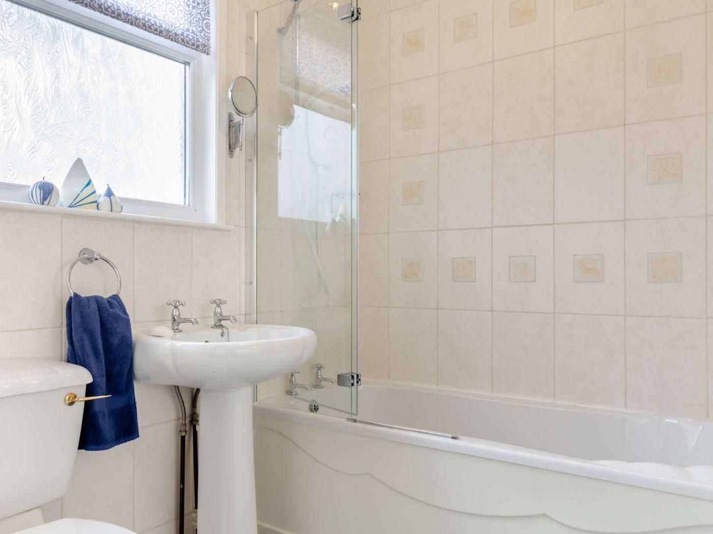 A bathroom with a white sink, a toilet, a bathtub, and a glass-enclosed shower.
