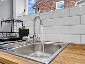 A stainless steel kitchen sink with a modern faucet, a dish rack, and a window with a view of a brick building. - Family lux home/6-car drv/ pool table/projector/ (Chadderton)