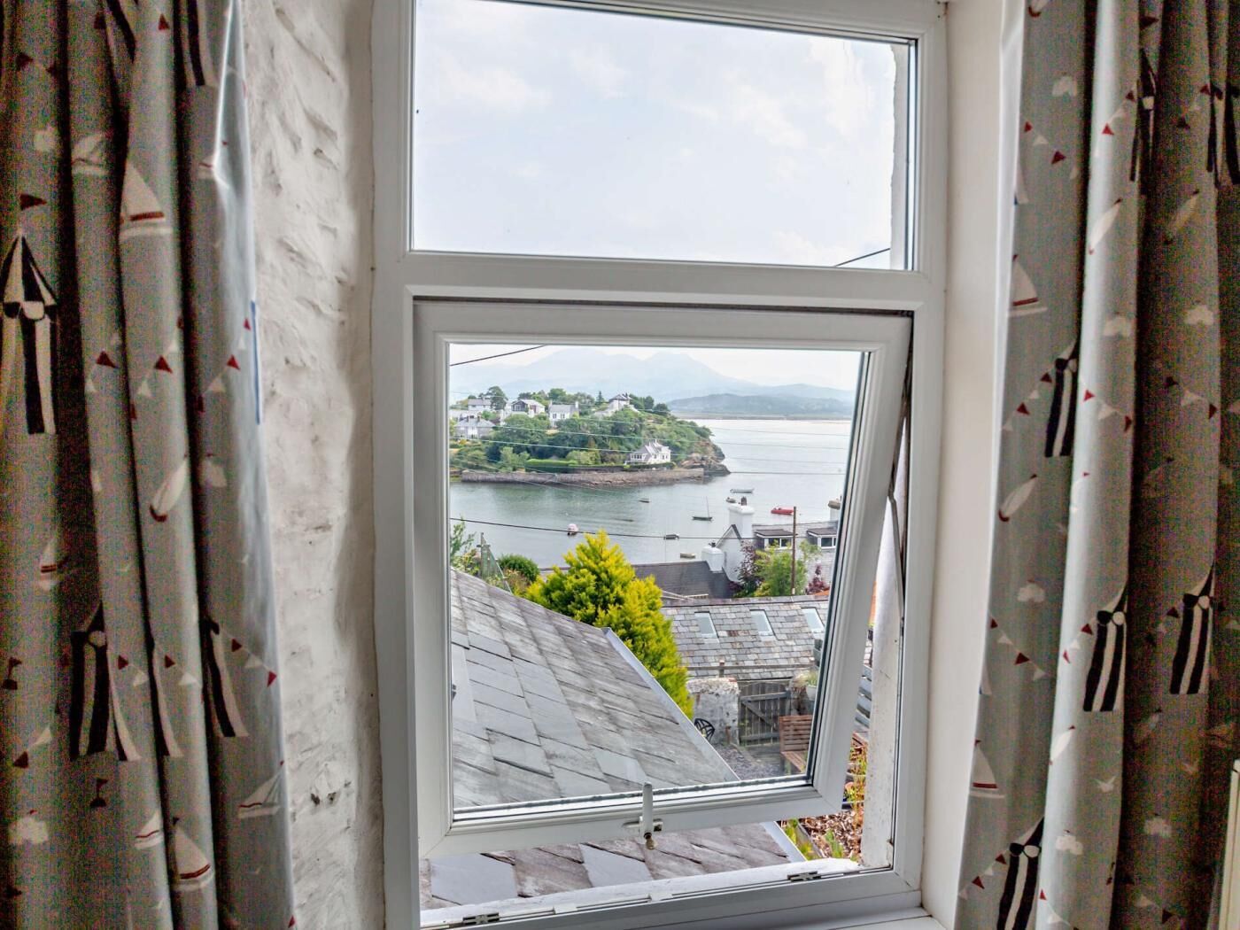 A window with a view of a coastal town, a clear sky, and a body of water.