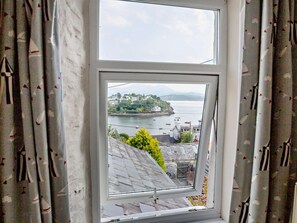 A window with a view of a coastal town, a clear sky, and a body of water. - 3 Bed in Porthmadog (oc-90615) (Borth-y-Gest)