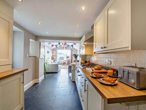Een keuken met een centraal eiland, een eethoek en uitzicht op de woonkamer.