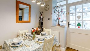 A dining area with a table set for four, a mirror, a clock, and a window with decorations. - 1 Bed in Whitby (oc-90699) (Fylingdales)