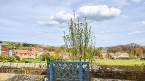 A stone wall with a wooden gate, a clear sky, and houses in the background. - 1 Bed in Whitby (oc-90699) (Fylingdales)