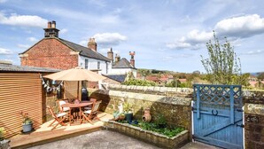 A patio with a table and chairs, a blue gate, and a stone wall. - 1 Bed in Whitby (oc-90699) (Fylingdales)