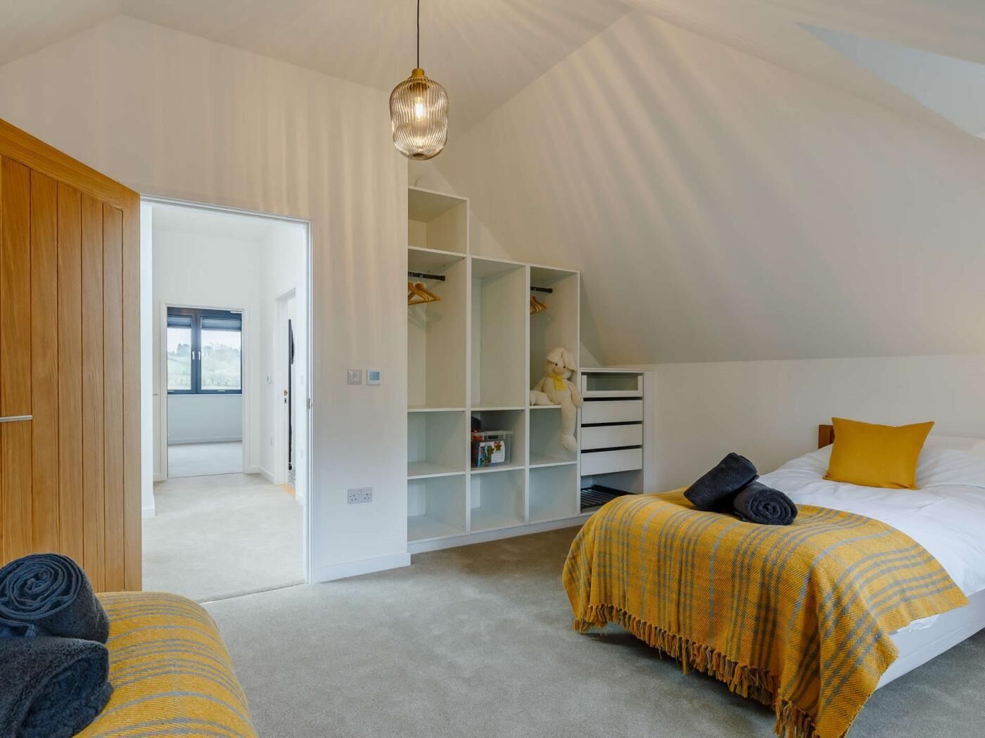 A bedroom with two beds, a wardrobe, and a hanging light fixture.