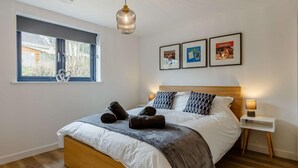 A bedroom with a bed, a window, a bedside table, and wall art. - 3 Bed in Holsworthy (oc-90721) (Holsworthy)