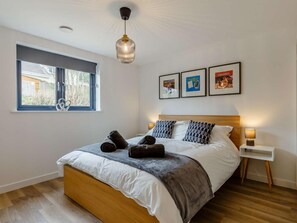 Ein Schlafzimmer mit Bett, Fenster, Nachttisch und Wandbildern.