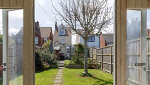 Een tuinpad dat leidt naar een huis met een houten omheining en een boom.
