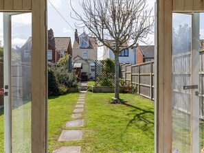 A garden pathway leading to a house with a wooden fence and a tree. - 3 Bed in Sheringham (oc-90701) (Sheringham)