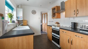 Een moderne keuken met houten kastjes, een zwart aanrecht en een roestvrijstalen afzuigkap.