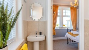 A bathroom with a sink, mirror, and potted fern. - 3 Bed in Seahouses (oc-90727) (Seahouses)