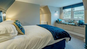 Un dormitorio con cama, una ventana con asiento y un radiador.