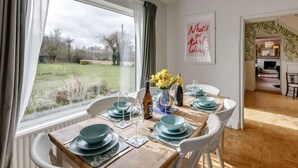 A dining area with a table set for four, a view of the outdoors, and a framed quote on the wall. - 3 Bed in Malvern (oc-90775) (Mathon)