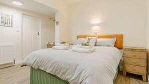 A bedroom with a bed, a nightstand, a dresser, a radiator, and a door leading to another room. - 3 Bed in Whitby (oc-90809) (Aislaby)