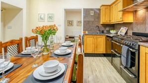 A modern kitchen with wooden cabinets, a gas stove, and a dining area with a table set for four. - 3 Bed in Whitby (oc-90809) (Aislaby)