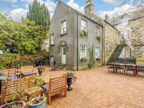 A stone building with a green door, outdoor seating, and a brick patio. - 5 Bed in Dunkeld (oc-90844) (Birnam)