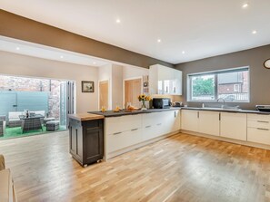Eine moderne Küche mit weißen Schränken, einer Holzausziehtafel und einem großen Fenster.