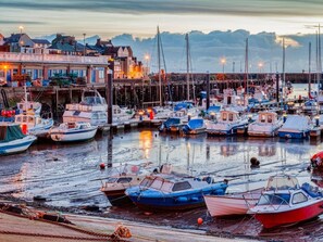 Un porto turistico con barche ormeggiate, un molo con edifici e una vista sul lungomare.