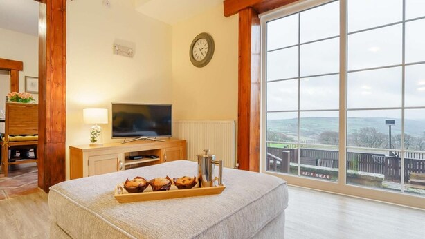 Ein geräumiges Zimmer mit großem Fenster, einem Fernseher, einer Uhr und einer Muffinschale.