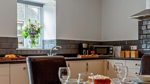 Ett modernt kök med matplats, utrustat med ett fönster med blommor, en mikrovågsugn och en kaffebryggare.