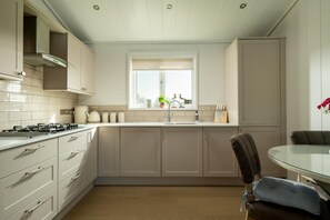 A modern kitchen with a gas stove, cabinets, and a window with a view. - 2 Bed in Castle Douglas (oc-90821) (Auchencairn)