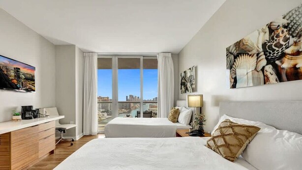 Ein Hotelzimmer mit Blick auf die Stadt, einem Bett, einem Schreibtisch und einem Fernseher.